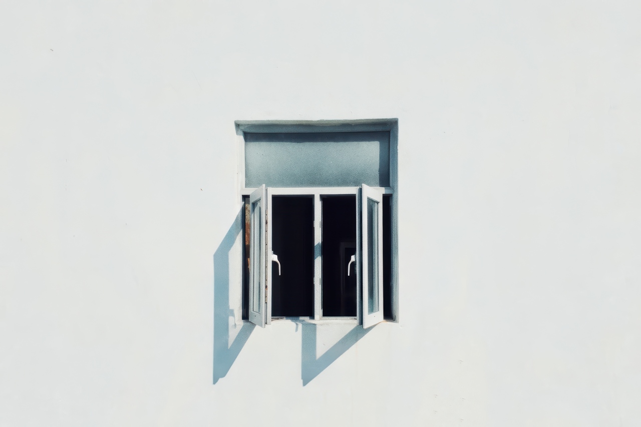 A small white double-casement window swung open on a plain white exterior wall, the type of open window that can cause AC systems to work harder and lead to uneven cooling.
