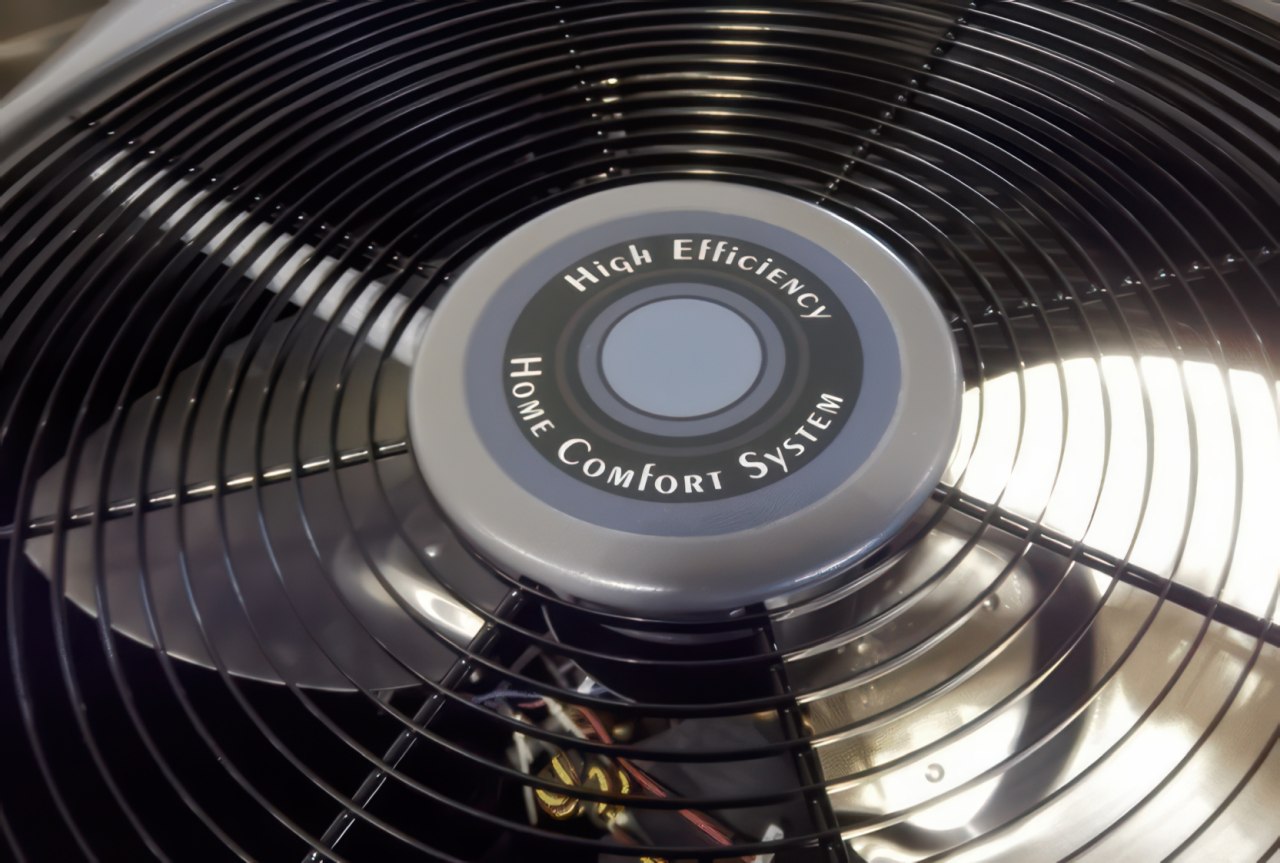 A close up photograph shows the top grille and fan blades of an air conditioner with a central cap labeled High Efficiency Home Comfort System.