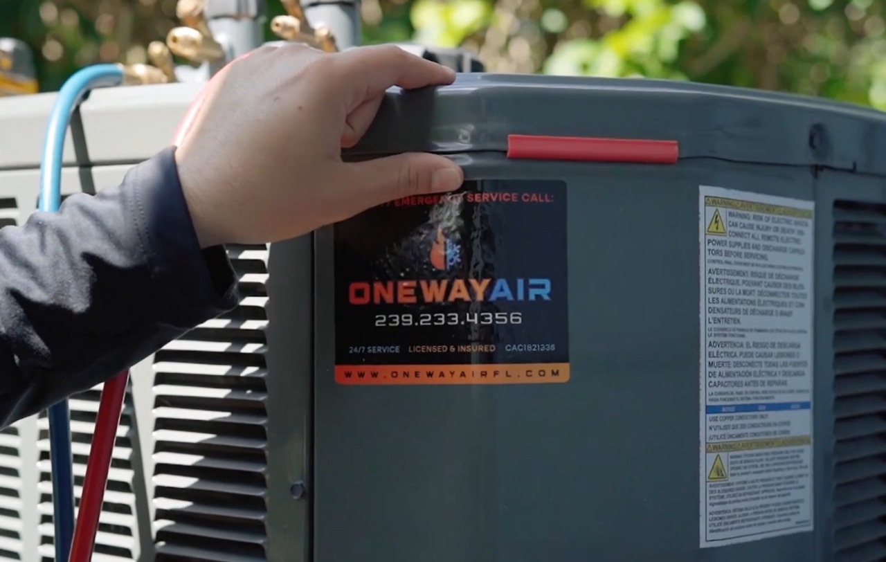 A technician’s hand rests on a heat pump unit labeled “ONEWAY AIR” during an installation or service in Florida.