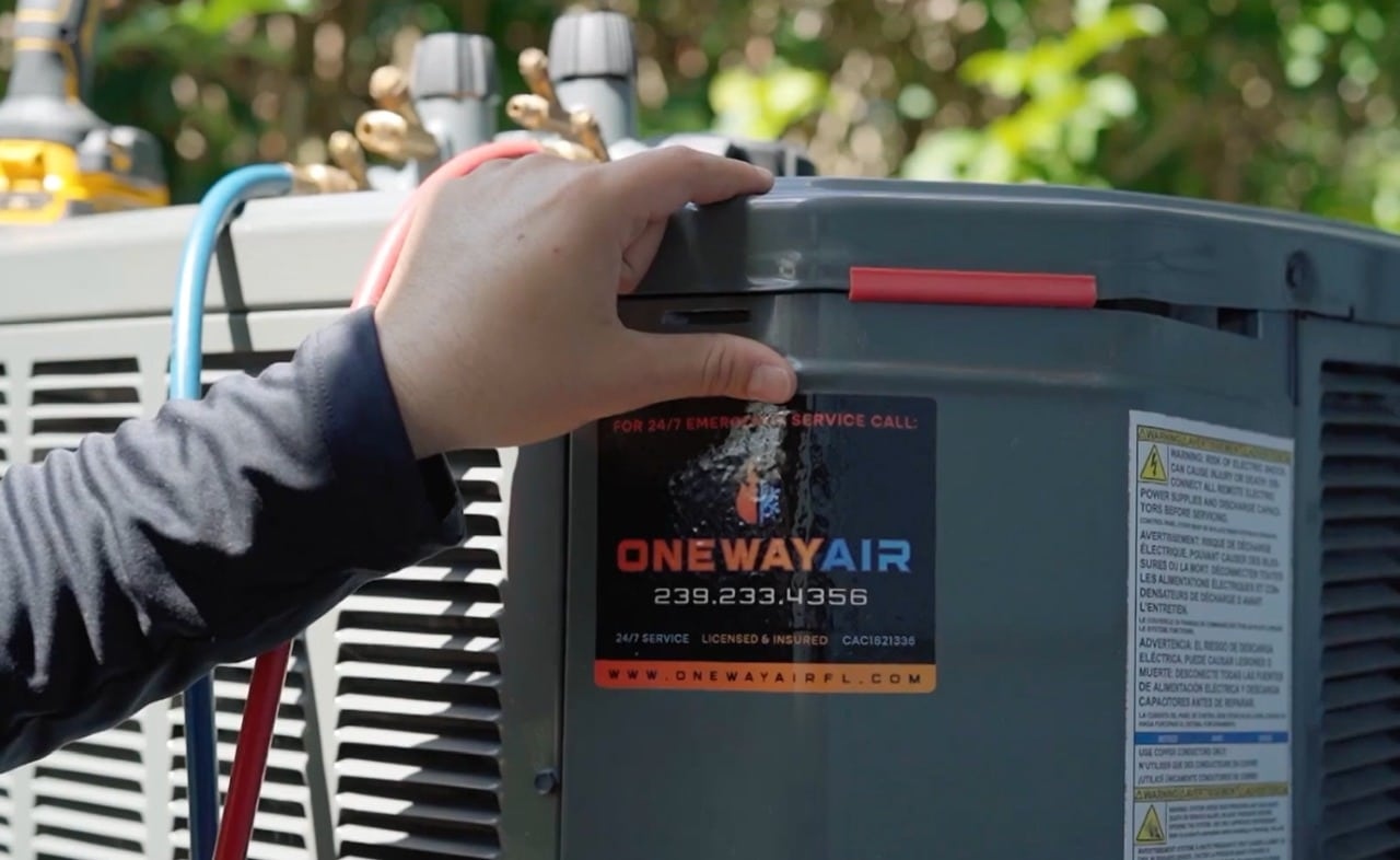 Technician working on an outdoor HVAC unit labeled 'ONEWAY AIR'.
