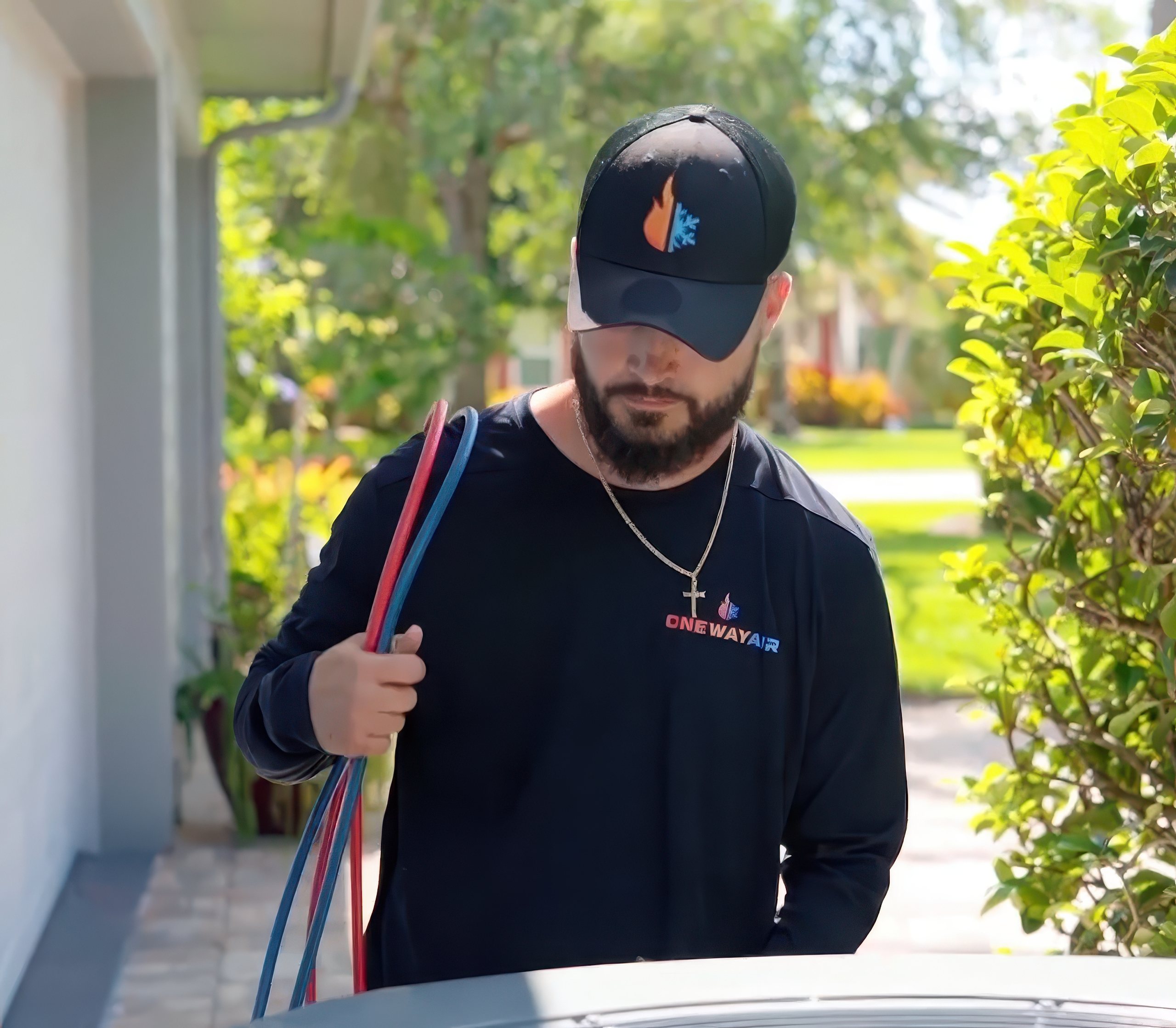 HVAC technician from One Way Air carrying service hoses outside a home, representing professional AC repair cost in SWFL and reliable local service.